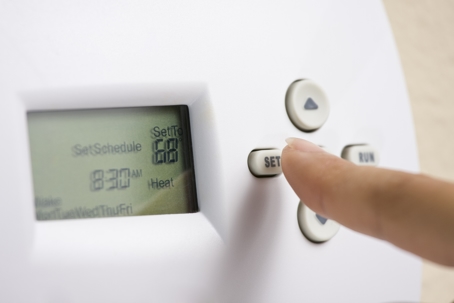 A white thermostat with the temperature set to 68 degrees