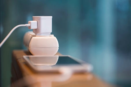 A white power outlet with a cord plugged in, and a phone nearby.