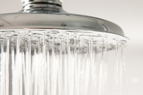A chrome shower head with water spraying down.