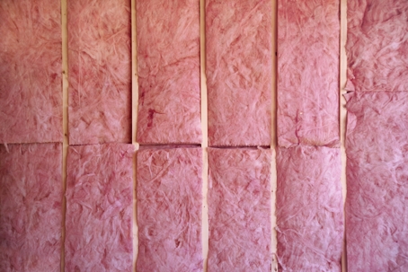 Pink insulation boards are installed between wooden studs.