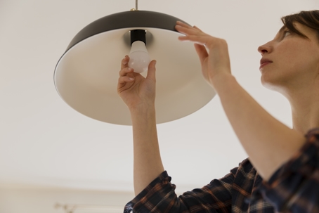 A person is changing a lightbulb in a hanging lamp.