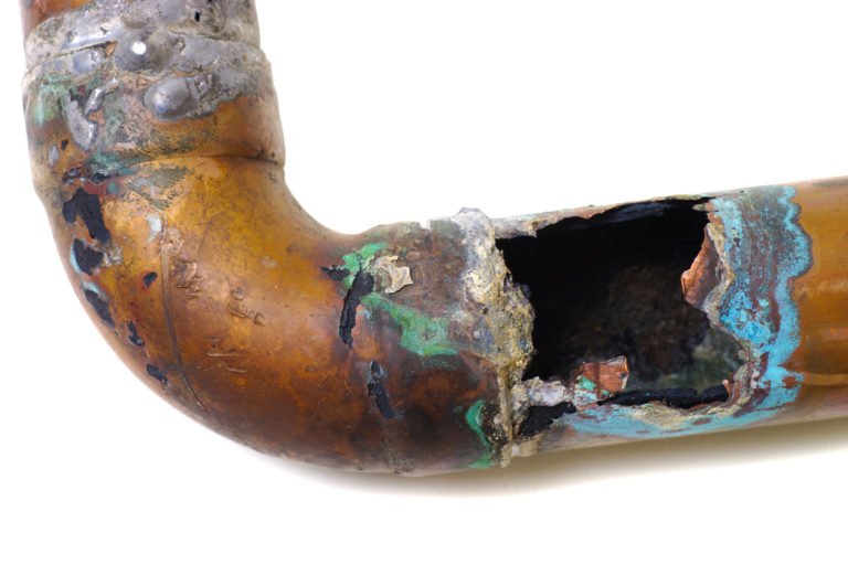 A corroded and damaged copper pipe with a large hole.
